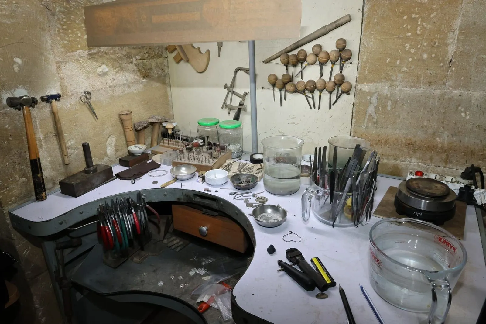 De werkbank in het atelier, met hamers, tangen en bakjes