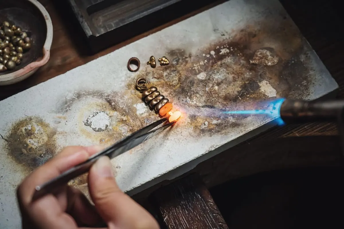 Een vlam van een brander bij een sieraad op de werkbank
