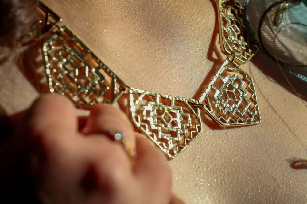 Een gouden collier met geometrische schakels, gedragen